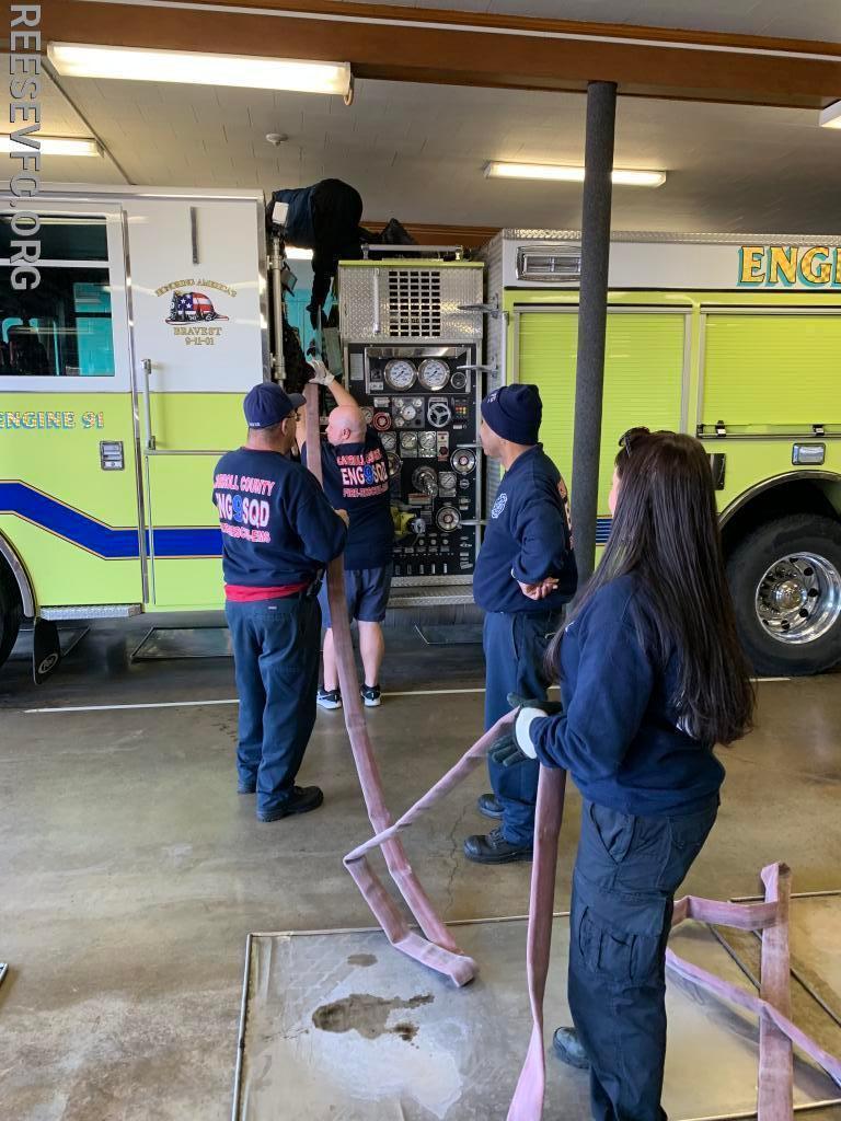 Paid staff personnel and volunteer members working together to rack hose.